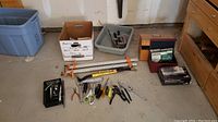 Wide view of floor space with various clamps, hand tools, and boxes containing sanding supplies.