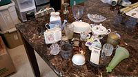 Overview of the collection on a marble table including various small porcelain, glassware, metal, and decorative items showing condition and assortment.