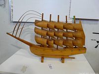 Side view of the large wooden boat model showing the multiple curved sails and the attached base