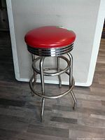 Full view of the chrome high stool with red faux leather seat showing its structure and condition.