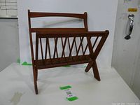 Wood folding magazine rack with slatted design, shown unfolded and standing upright against a white background.