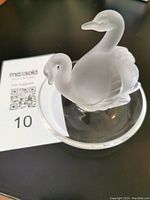 Top angle photo showing the frosted crystal swans on a clear round base, highlighting the detail on the swans and the overall design.