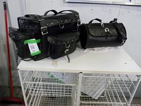 Front and side view of three black leather motorcycle bags arranged on a white surface, showing size difference and metal studded decorative details.