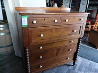 Front view of entire highboy dresser showing six drawers, porcelain knobs, turned side columns