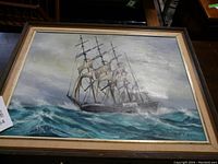 Full view of oil painting showing a sailing ship in rough seas, framed