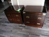 Pair of dark wood Koehler nightstands with brass handles viewed from front on grey wooden floor.