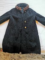 Full view of the black Persian lamb fur coat with mink collar laid flat, showing the overall style and length.