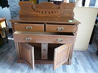 Front view of vintage wooden sideboard buffet with three drawers and two cabinet doors below, decorative wood backboard visible.