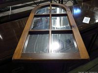 Front view of the wooden window frame style mirror showing its arched top and divided glass panels.