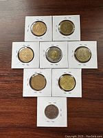 Photo showing all 8 coins in white cardboard holders on wooden surface, arranged in rows