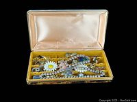 Open Mele tortoise shell jewelry case displaying multiple vintage jewelry pieces including silver charms, beads, and costume jewelry.