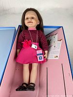 Full view of Maplelea Leonie doll standing inside original box showing outfit and accessories