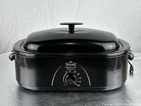 Full side and top view of black Rival electric roaster oven with lid on, showing overall shape and handles.