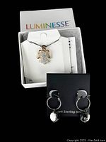 Sterling silver angel pendant necklace with Swarovski crystal details displayed on white jewelry holder inside Luminesse box.