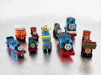 All 10 mixed Thomas and Friends metal and plastic railway cars shown grouped on a white background.