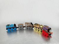 Front and side view of all five wooden railway cars including two engines and three train cars displayed in line.