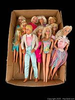 Full view of the lot showing 10 vintage Barbie dolls and 1 Ken doll with various dresses inside a cardboard box.