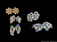 All five pairs of vintage clip-on rhinestone earrings displayed on black background for full lot view.