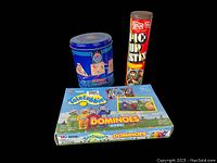 Three vintage games: Milton Bradley Teletubbies Dominoes game, Steven Pick Up Sticks in a tall tin, and Castle Classics wooden puzzles in a blue tin with instructions