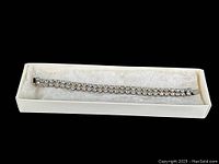 Bracelet shown in original box on a white padded background showing full length and clear rhinestones.