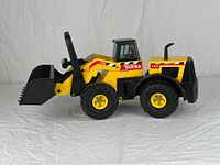 Side view of the vintage Tonka front end loader showing the yellow and black color scheme, brand and model decals, wheels, and loader arm.