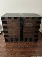 Front view of antique dark wood trunk with black metal banding and lock cover