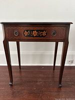 Front view showing drawer and floral inlay detail with metal ring pulls.