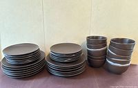 Photo of 12 large plates, 12 small plates, and 10 bowls, all brown IKEA dishes in good condition.