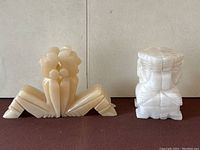 Photo showing the cream-colored onyx seated figure bookends with their backs to each other, arranged on a brown surface.