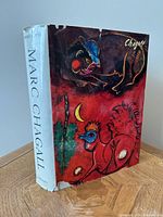Front cover of Marc Chagall art book with colorful dust jacket featuring Chagall artwork and some tears at the top and bottom edges.