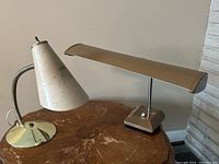 Photo showing both vintage desk lamps on wooden table against neutral wall.
