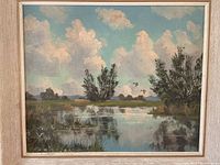 Front view of landscape painting showing water reflection, trees, sky with clouds, and birds under wood frame.