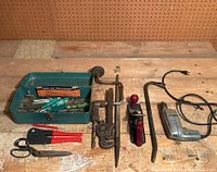 Photo showing vintage green metal tool box and various classic hand tools spread out on wooden surface.