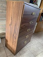 Side view showing brown wood grain laminate finish and five drawers with metal pull handles.