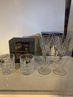 Photo of all glasses showing 8 tall champagne glasses and 4 short whiskey glasses with original boxes in the background.