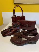 Overview photo showing two pairs of shoes and two handbags arranged on a flat surface against a yellow background.