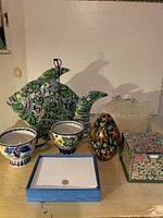 Photo showing the collection of various gift items including the metal fish tea light holder, oversized candles, ceramic mugs, stationery and note pad holder, and floral stationery box all arranged on a surface.