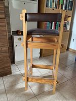 Side profile shot showing the wooden frame construction and dark brown faux leather upholstery on seat and backrest.