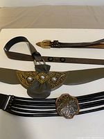 Four ladies fashion belts displayed flat showing unique buckles and clips