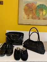 Photo showing two black vinyl handbags with croc-embossed texture and two pairs of black shoes including velvet slippers and synthetic leather comfort sole shoes, all arranged on a table.