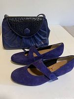 Photo showing the periwinkle blue suede shoes with Mary Jane strap and matching handbag with black textured flap.