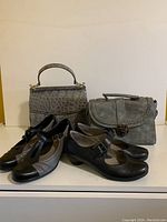 Two pairs of new ladies shoes size 7, and two grey-tone handbags with straps on display.