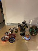 View of entire lot showing all pots, dishes, ginger jar, glass floral tree, and vase on wooden surface against white background.