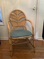 Front view of rattan chair with cushioned seat and decorative backrest