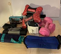 Full lot showing dumbbells, hand weights in box, ankle weights, and foam pillows all arranged on table.