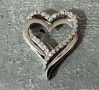 Close-up photo of a heart-shaped sterling silver pendant with diamond accents