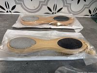 Two new bamboo foot files, packaged, showing metal grater and pumice surfaces on wooden handles.
