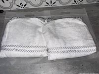 Two white hooded towels with gray striped borders, laid flat to show size and hood details with ears.