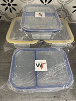 Four glass casserole dishes stacked, each with plastic storage lids wrapped in plastic.