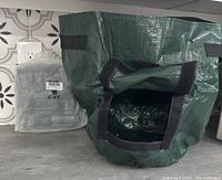 Green 7-gallon grow bag opened to show Velcro flap access hole and drainage holes for harvesting root vegetables.